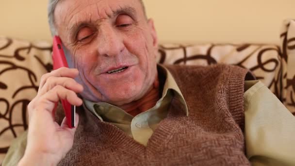 starší muž s červeným smartphone mluví - Záběry, video