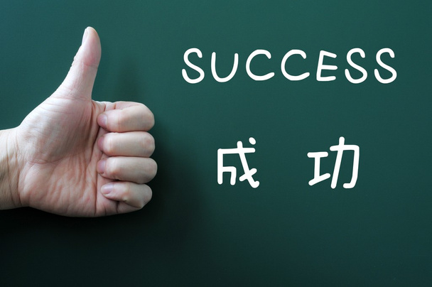 succes geschreven op een schoolbord met een duim omhoog - Foto, afbeelding