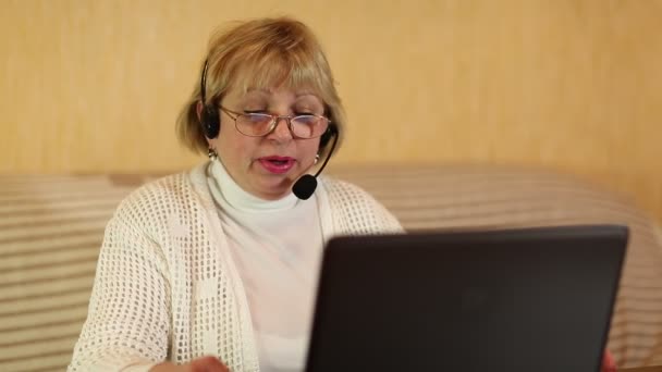 Γυναίκα με τα ακουστικά με μικρόφωνο μιλά σε έναν πελάτη μέσω υπολογιστή - Πλάνα, βίντεο