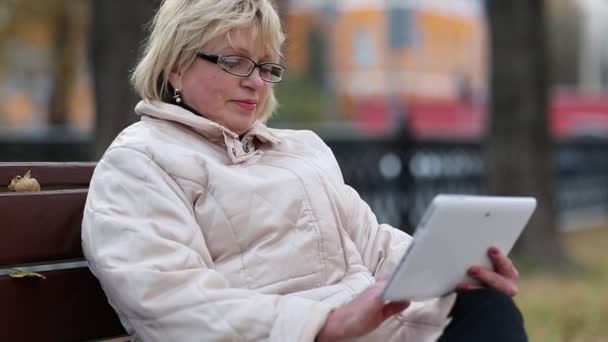 Mulher senta-se no banco e usa computador tablet. Mulher com Tablet PC
 - Filmagem, Vídeo