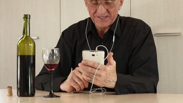 Человек с сотовым телефоном сидит за столом и пьет вино
 - Кадры, видео