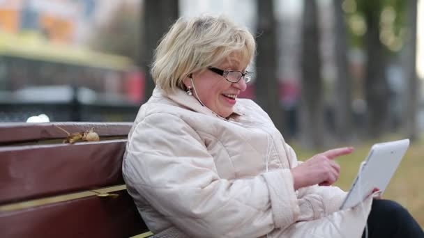 Donna anziana si siede sulla panchina vicino alla strada e comunica tramite tablet PC
 - Filmati, video