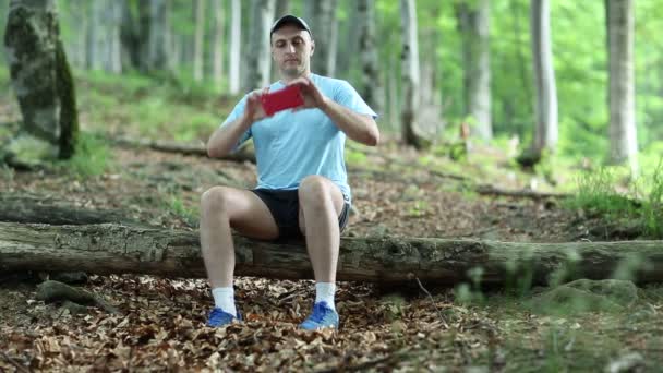 man sits on a fallen tree and makes photos - Footage, Video