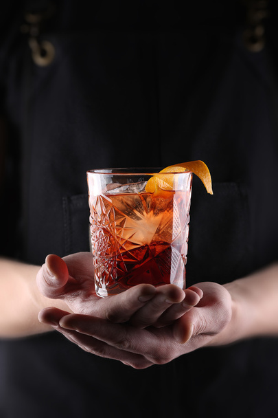 Old fashioned Negroni cocktail in hand on the black background - Foto, afbeelding
