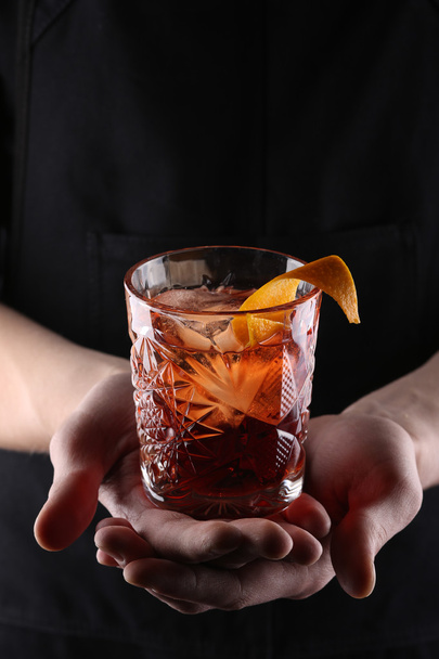 old fashioned Negroni cocktail in hand on the black background - Фото, изображение