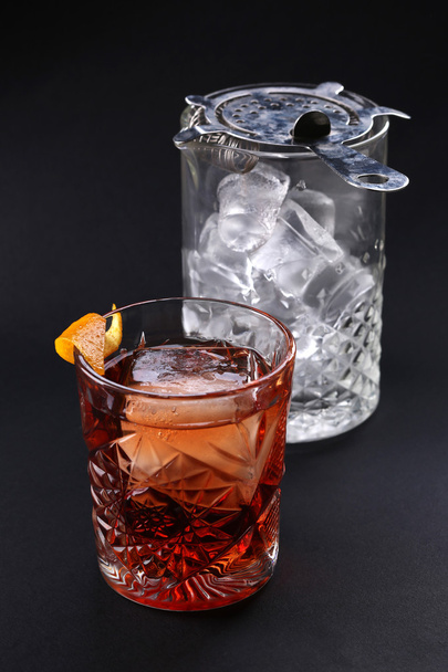 Old fashioned Negroni cocktail near glass with ice on the black background - Фото, изображение