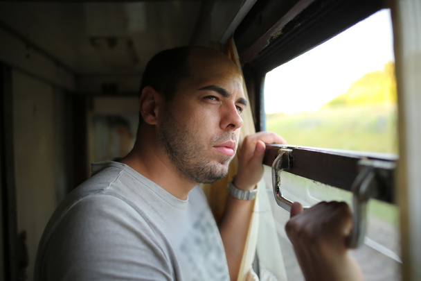 Handsome man looking out the open train window outside - Foto, afbeelding