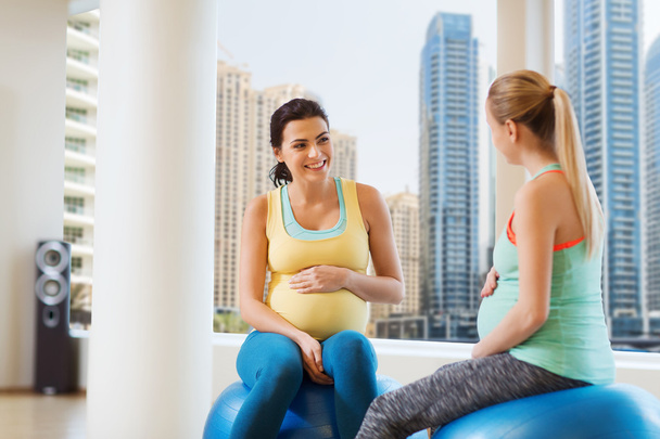 two happy pregnant women sitting on balls in gym - Foto, Imagem