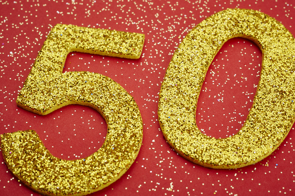 Number fifty golden color over a red background. Anniversary - Foto, Imagen