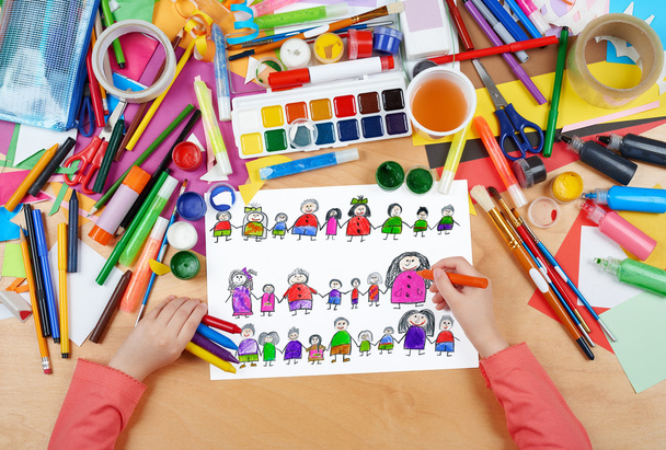 child drawing cute happy cartoon people in row, top view hands with pencil painting picture on paper, artwork workplace - Photo, Image