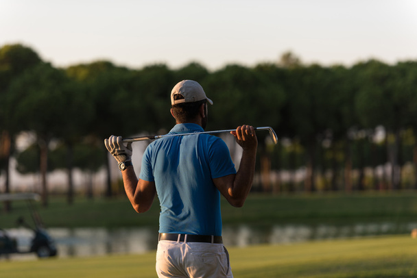 гольфист со спины на курс ищет отверстие в расстоянии
 - Фото, изображение