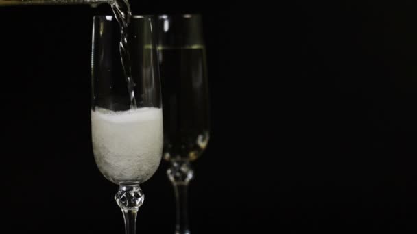 Champagne wordt gegoten in een glas op een zwarte achtergrond - Video