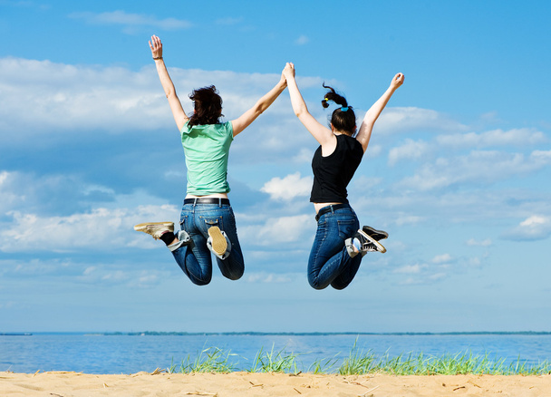 Two happy women jumping on the beach - Photo, Image