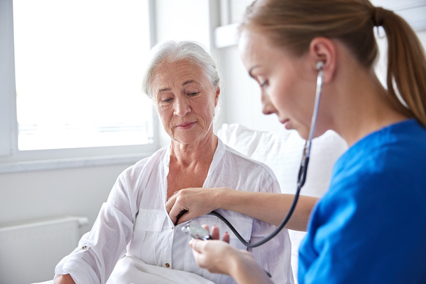 nurse with stethoscope and senior woman at clinic - Foto, Bild