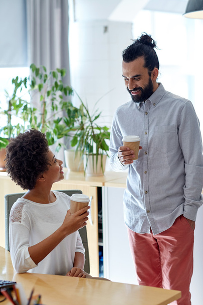 happy man and woman drinking coffee in office - Foto, Imagen
