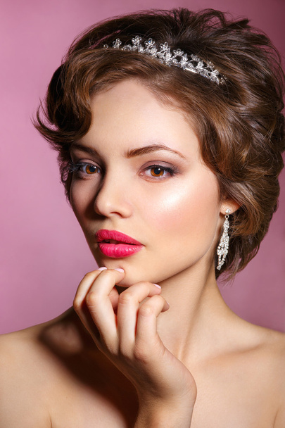 Portrait of beautiful bride. Wedding dress. Wedding decoration.Portrait of a beautiful woman in the image of the bride with jewel in her hair. Picture taken in the studio on a pink background. - Foto, imagen
