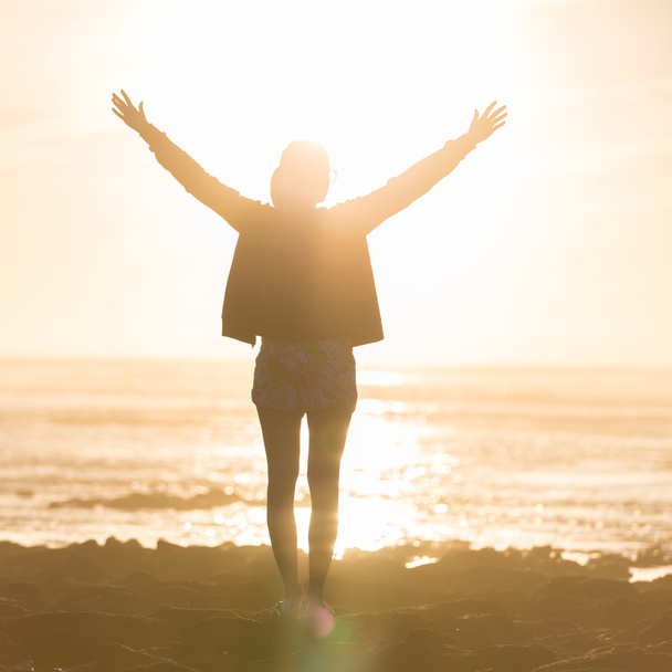 Вільна жінка насолоджується свободою на пляжі на заході сонця
. - Фото, зображення