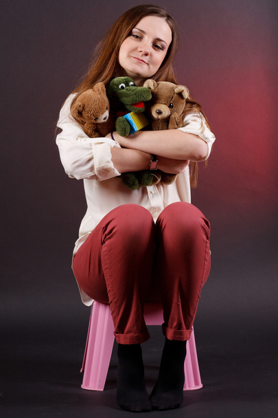 Girl with soft toys sitting on a chair - Foto, immagini