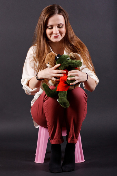 Girl with soft toys sitting on a chair - Zdjęcie, obraz