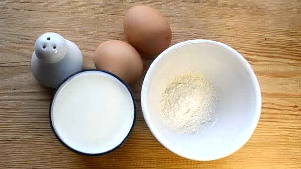 Nasypany flour and milk in a bowl. Ingredients milk, salt, eggs, flour - Кадры, видео