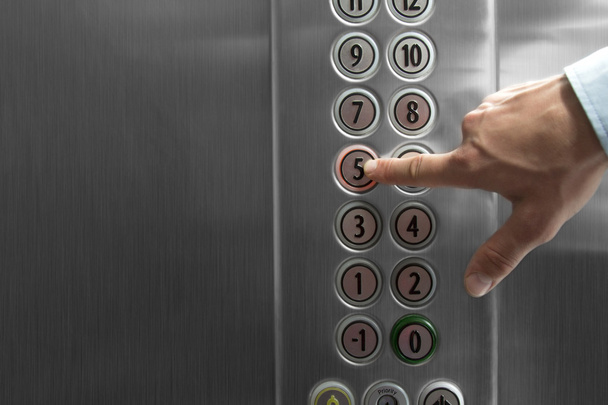 Forefinger pressing the fifth floor button in the elevator - Foto, Imagen