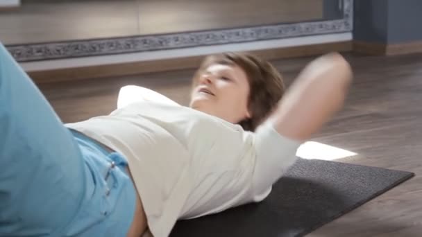 Mujer mayor activa haciendo abdominales ejercicios de ejercicios
 - Metraje, vídeo