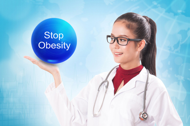 Female doctor holding blue crystal ball with stop obesity sign on medical background. - Photo, Image