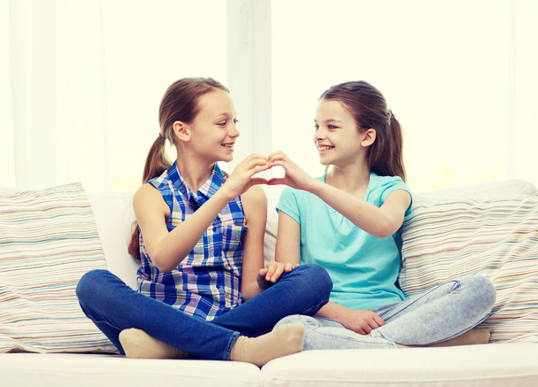 happy little girls showing heart shape hand sign - Foto, imagen