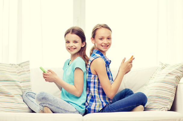 happy girls with smartphones sitting on sofa - Фото, изображение