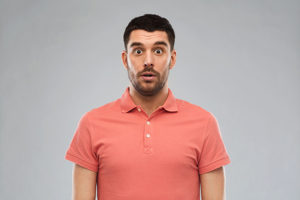surprised man in polo t-shirt over gray background - Photo, image