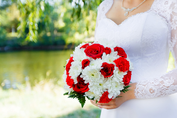 Brides hands holding bridal bouquet of red roses and white chrysanthemum close up - Zdjęcie, obraz