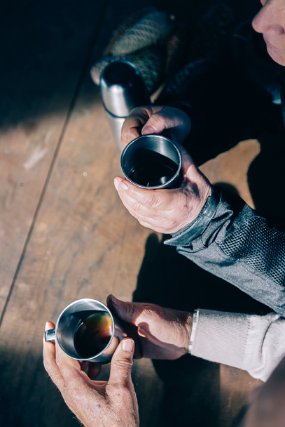 Старша пара рук тримає чашки з кавою
 - Фото, зображення