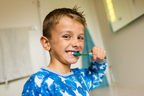 Молодий хлопчик чистить зуби зубною щіткою
 - Фото, зображення