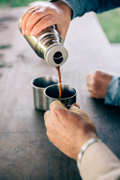 Starší pár ruce naléval kávu z termosky - Fotografie, Obrázek