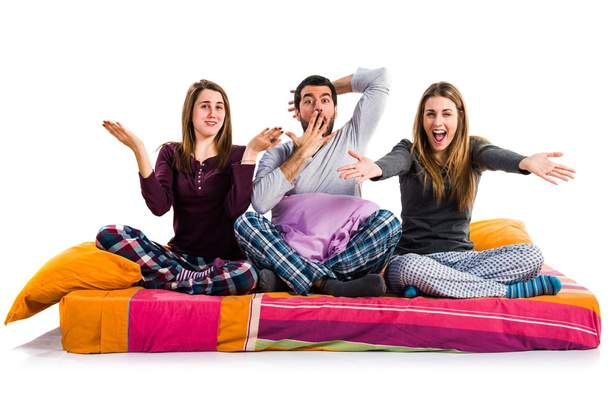 drei Freunde auf einem Bett mit Überraschungsgeste - Foto, Bild