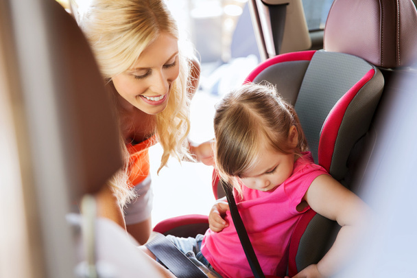 happy mother fastening child with car seat belt - Photo, image