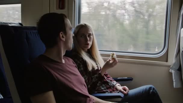Pareja joven viaja en tren, come sándwich y utiliza la tableta para navegar
 - Imágenes, Vídeo