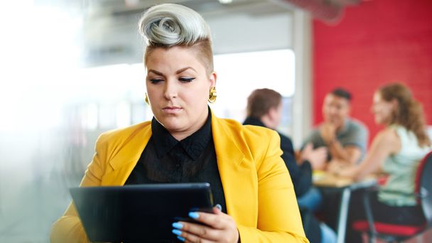 selbstbewusste und kantige Designerin, die im roten Kreativbüro an einem digitalen Tablet arbeitet - Foto, Bild