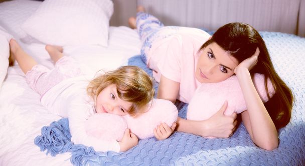 Romantic atmosphere mother and daughter hugging pink soft hearts in bed - Foto, Bild