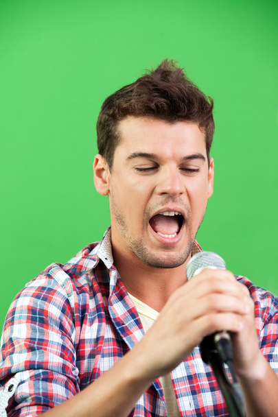 Male Singer Performing Against Green Wall - Foto, Imagen