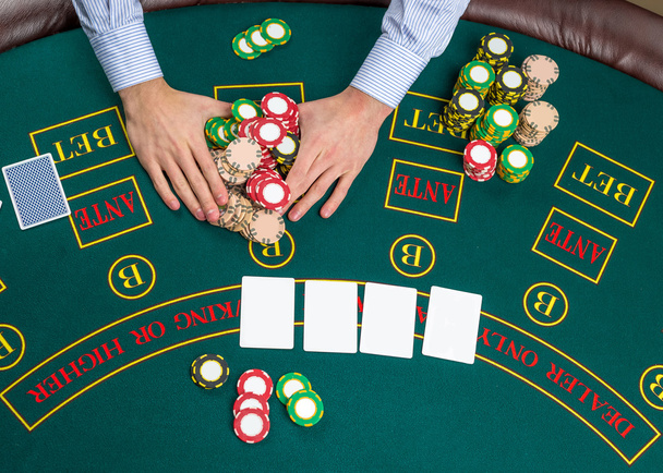 Nahaufnahme eines Pokerspielers mit Spielkarten und Chips - Foto, Bild