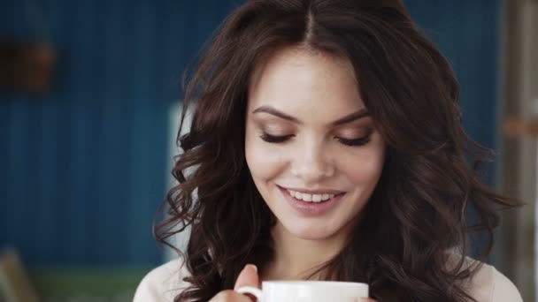 Gelukkig meisje koffie drinken en ontspannen in het café, glimlachen en kijken naar camera. - Video