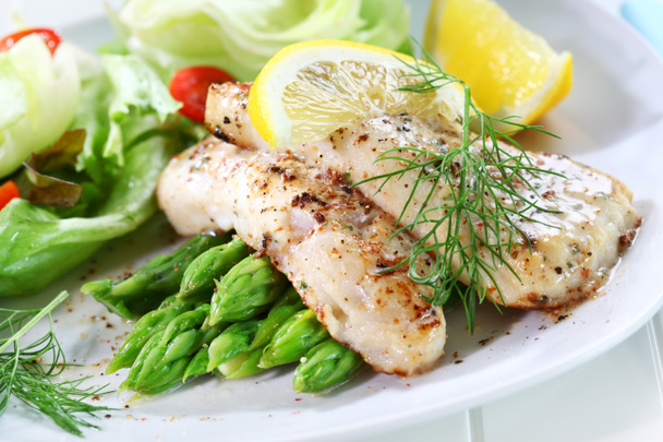 Fried fish on green asparagus with salad - Photo, Image