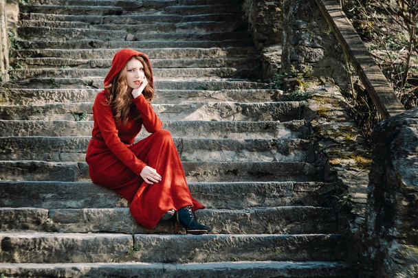 Szép nő, piros ruhás, régi lépéseket ült - Fotó, kép