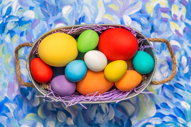 Kleurrijke paaseieren op lichte achtergrond. Paasvakantie. Veelkleurige achtergrond groene, blauwe en paarse kleuren. Pasen eieren in een mand. - Foto, afbeelding