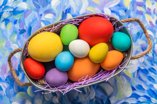 Parlak arka plan üzerinde renkli Paskalya yumurtaları. Paskalya tatili. Çok renkli arka plan renkleri yeşil, mavi ve mor. Paskalya yumurtaları bir sepet içinde. - Fotoğraf, Görsel