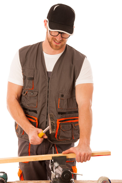 Handyman in work clothing hammering nail with hammer in home wor - Фото, изображение