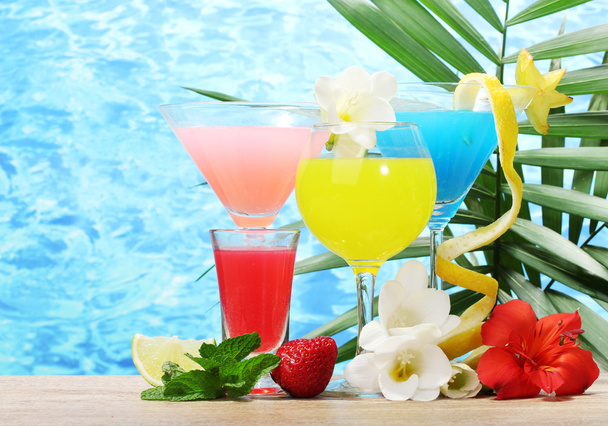Exotic cocktails and flowers on table on blue sea background - Fotoğraf, Görsel