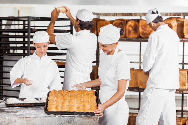 Baker Looking At Baked Breads In Bakery - Foto, afbeelding