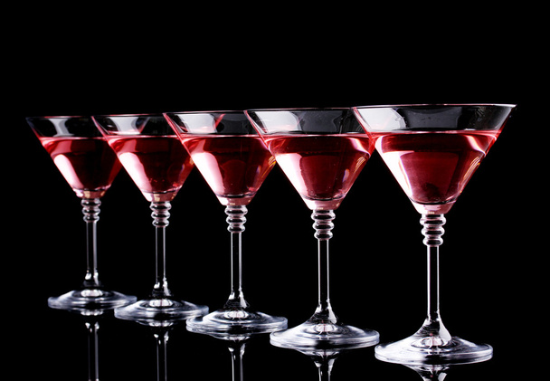 Red cocktail in martini glasses isolated on black - Photo, image